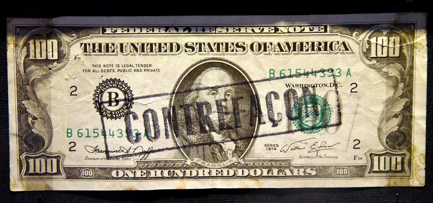 A counterfeit Series 1974 one-hundred-dollar bill on display at the British Museum overprinted with a rubber stamp to indicate that it is a fake.