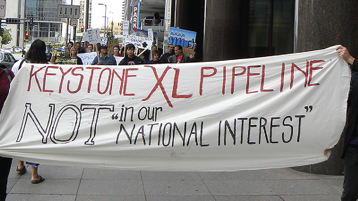 A banner held by people that reads “Keystone XL pipeline not in our “national interest”.”