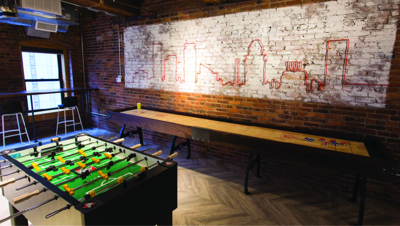 This image shows a room with a shuffleboard table and a foosball table.
